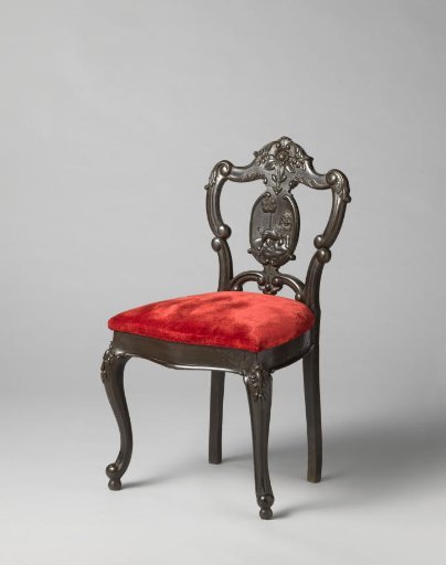 Chair with relief of an elephant and driver in the back. Loose seat upholstered in red velvet