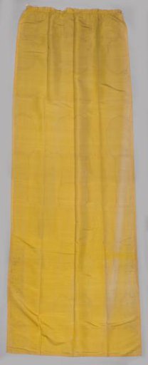 Curtain, yellow, trimmed with passementerie featuring palmettes and curved ribbons.