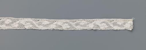 Strip of bobbin lace with a continuous vine with a few flowers