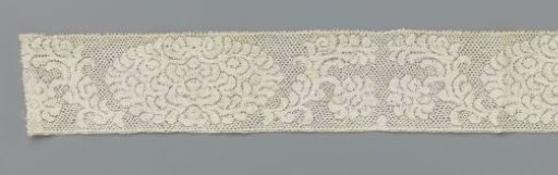 Strip of bobbin lace with peonies and loose dots along the upper edge