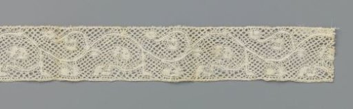 Strip of bobbin lace with curling slender tendrils with stylized flowers and leaves