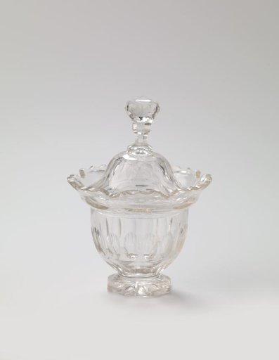 Sugar pot of cut crystal. Bowl-shaped, with sloping scalloped rim on which a vaulted lid with knob. Entirely on octagonal foot.