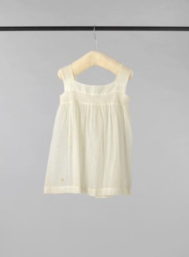 Sleeveless children's dress of white cotton with a diamond pattern of drawn work, decorated on the bodice with openwork crochet
