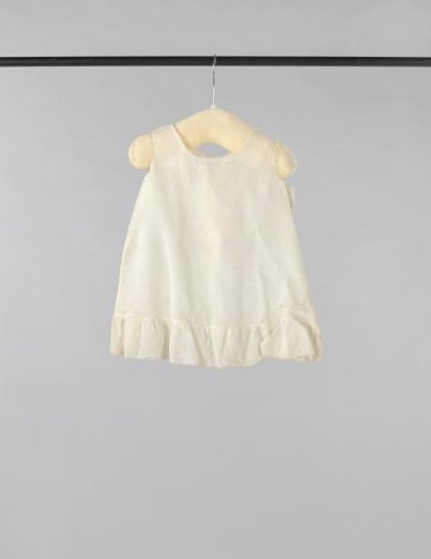 Sleeveless children's dress of white cotton (?), decorated with white embroidery with purl stitches and flower and leaf motifs and drawn work; standing collar and crocheted edge along the armholes