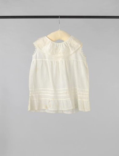 Sleeveless children's dress of white batiste, decorated on the collar and skirt with white embroidery and on the skirt also with three drawn work sections at the hem; crocheted edge along the armholes