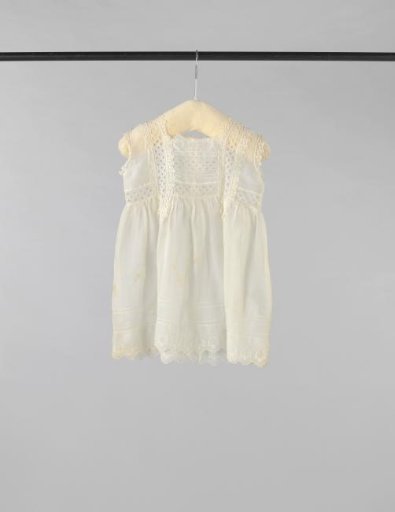 Sleeveless children's dress of white linen (?), decorated with white embroidery, drawn work, openwork inserts with a diamond pattern and edge borders; angular scalloped hem