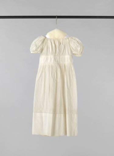 Children's dress of white linen with a short puff sleeve, a short bodice with fine pleats, a wide smooth waistband and a finely pleated skirt, decorated with English embroidery