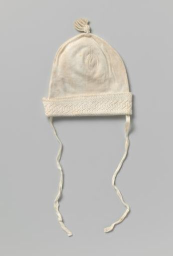Knitted cap of white cotton with very fine stocking stitch, a tassel on top and turned-up edge with openwork; marked in red cross-stitch: VG4