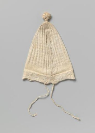 Knitted cap of white cotton with a tassel on top and a zigzagging scalloped turned-up edge with openwork