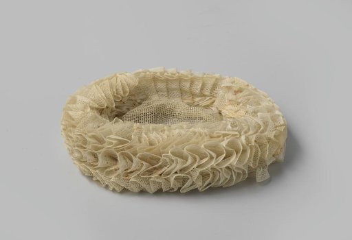 Maid's cap of tulle netting, consisting of a flat oval center surrounded by a triple, ruffled border