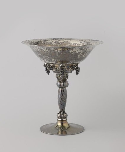 Fruit bowl, round, on a low vaulted foot with a high stem, among other things decorated with grape clusters