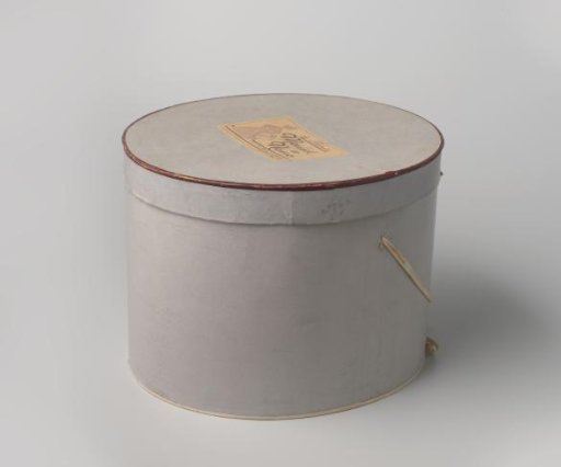 Oval cardboard hatbox, covered with light grey or light blue paper trimmed with a brown braid on the lid