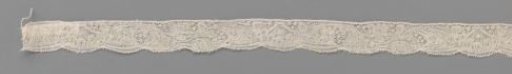 Strip of bobbin lace with elongated wavy acanthus leaf and calyx flower in horn-shaped motif