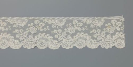 Strip of machine-made lace with a large flower beneath a floral arch and a recurved flower branch above