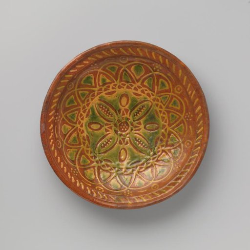 Dish on three shell-shaped feet, decorated with a large rosette motif of white slip, locally green lead glaze