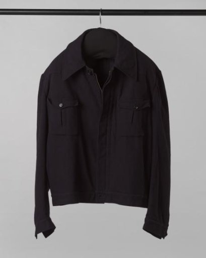 Jacket or blouson of navy blue worsted wool, with concealed fastening including a zip, two breast pockets with flap, long sleeves with cuffs and button, and flat pointed collar