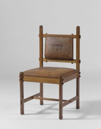 Oak chair upholstered in brown leather with a flower in the center of the seat and a branch on the back