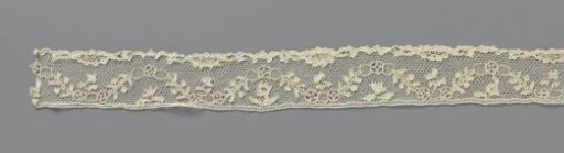 Band of needle lace with ovals on tops and in valleys of wavy leafy branch