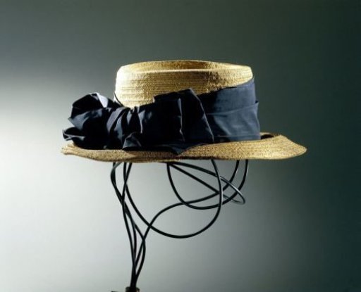 Hat of woven straw band with a straight crown and wide, drooping brim, decorated with a knotted black grosgrain ribbon