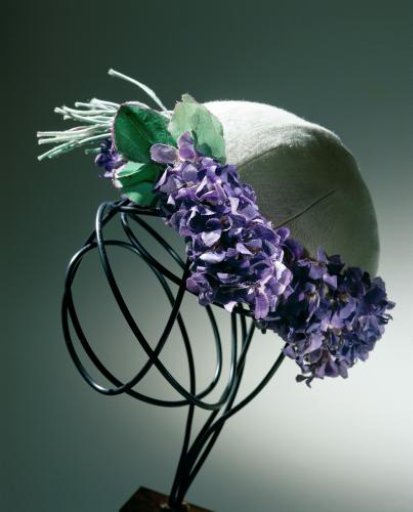 Cap of cream-colored woolen tricot decorated with a corsage and a border of 'violettes de Parme'