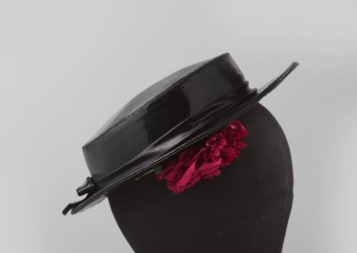 Hat with low, flat crown and flat brim of shiny black fabric, decorated with a cotton red rose under the brim