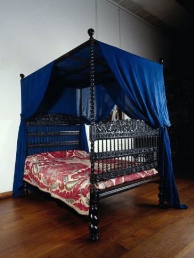 Bed of ebony with a cotton canopy. Swirled posts and lotus leaf decoration on thresholds and houses.