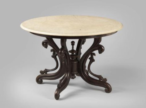 Round table of black tropical wood with a white marble top and C-scroll legs. So-called spider table