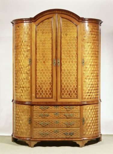 Cabinet with rectangular central section projecting forward, flanked by two quarter-round sections. Oak, veneered with various types of wood and fitted with copper hardware.