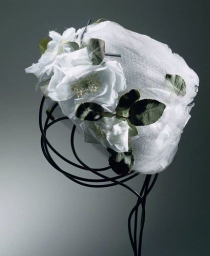 Hat of draped light blue tulle decorated with light blue rose petals and green leaves
