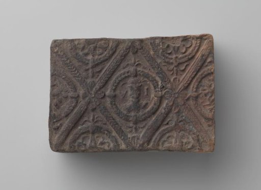 Fireplace with a man's head and the letters V I in a laurel wreath
