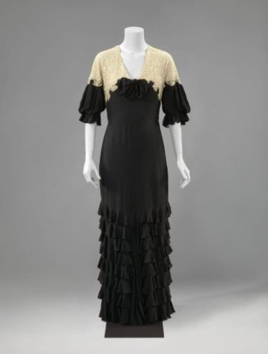 Evening Gown of Black Crepe Georgette and Natural Machine-Made Lace, Long and Slightly Dragging, Decorated with Ruffled Strips of Crepe Georgette