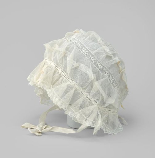 Cap of white tulle with plume and ruffled applied strip of scalloped lace with picots