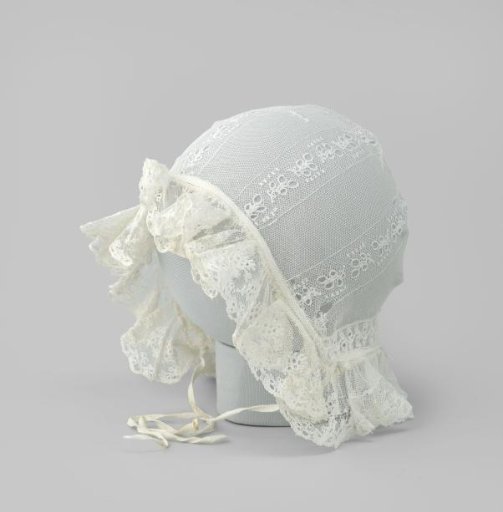 Baby cap of white tulle trimmed with a gathered applied strip of scalloped lace and a bow of two white ribbons