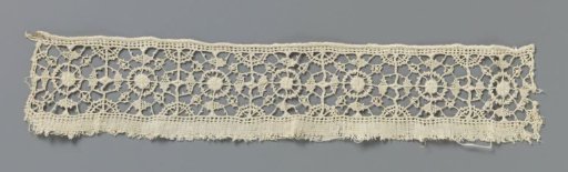 Strip of needle lace with concentric circles around a densely worked dot