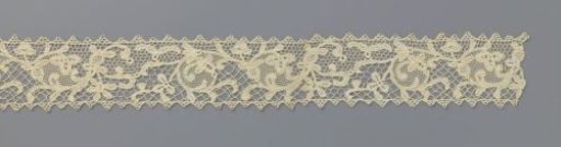 Strip of bobbin lace with volutes