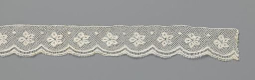 Strip of bobbin lace with rosette flower and dot