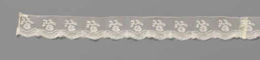 Strip of bobbin lace with hanging flower on branch