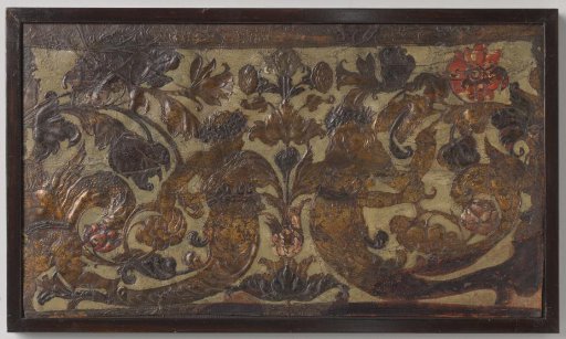 Border of raised gold leather, decorated with two facing sea creatures, floral and leafy scrolls in a symmetrical composition