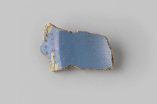 Fragment of yellow-fired earthenware, glazed blue on the front, with a painting of brown dots and yellow stripes on the rim