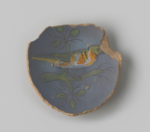Plate fragment of white-fired earthenware, glazed blue on the upper side, with a painting of a bird on a branch in green, orange, yellow and white