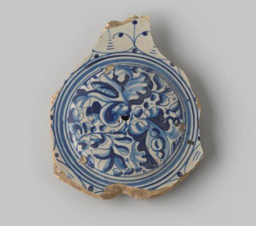 Plate fragment of white-fired earthenware, with footring, glazed colorless on the upper side, with a painting of curls, leaves and circles in blue