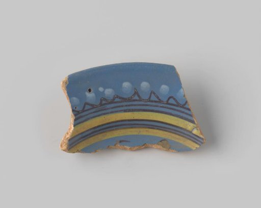 Fragment of red-firing earthenware, glazed on the upper side with blue glaze decorated with stripes and dots in brown, yellow and white