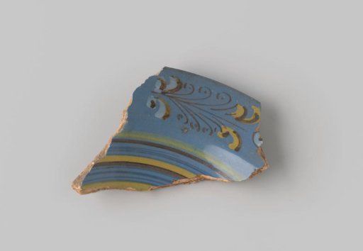 Fragment of red-firing earthenware, glazed on the upper side with blue glaze decorated with stripes and curls in brown, yellow, green and white
