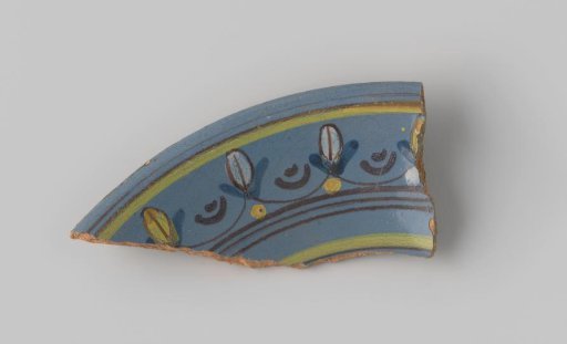 Fragment of red-firing earthenware, glazed on the upper side with blue glaze decorated with stripes and flowers in brown, yellow, green and white