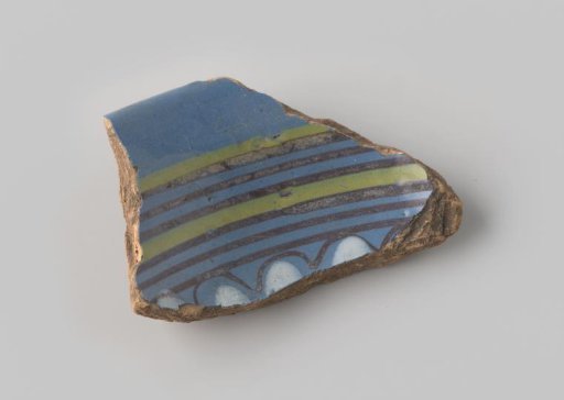 Fragment of red-firing earthenware, glazed on the upper side with blue glaze decorated with stripes and waves in brown, white and yellow