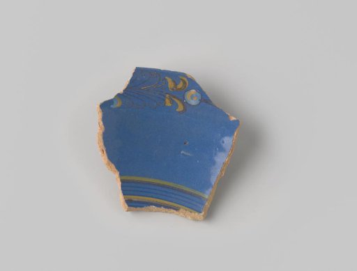 Fragment of red-firing earthenware, glazed on the upper side with blue glaze decorated with stripes in brown and yellow