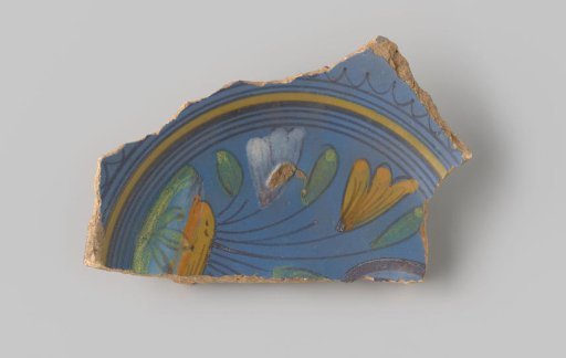 Sherd of reddish-baked earthenware, glazed blue on the upper side with a decoration of a scene of flowers growing in the earth in brown, white, yellow, orange and green, and several circles in brown and yellow around them