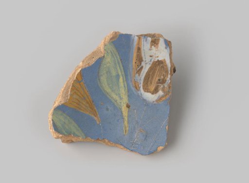 Fragment of reddish-fired earthenware, glazed blue on the upper side with a painting of two flowers in white, brown and ochre, and two green leaves