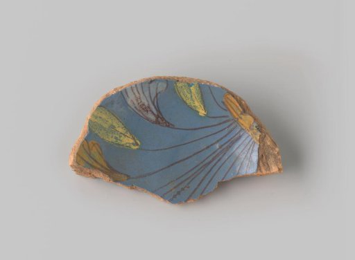 Fragment of reddish-fired earthenware, glazed blue on the upper side, painted with a part of a bush of flowers in earth tones, in yellow, orange, white and brown