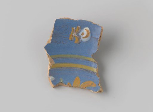 Fragment of reddish-fired earthenware, glazed blue on the upper side, with stripes in brown and yellow and stylized floral forms on either side in brown, white, yellow and green